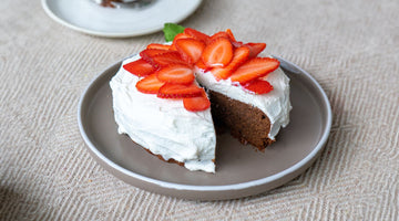 STEINER´s Schokokuchen, serviert auf einem grauen Teller. Der Schokokuchen ist getoppt mit Quark und frischen Erdbeerscheiben.