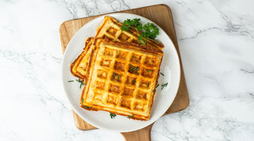 Waffeln mit Käse uns Speck im Teig liegen auf einem weißen Teller.