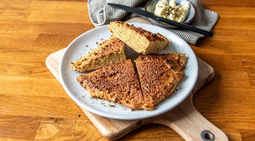 Ein rundes Fladenbrot in vier Stücke geschnitten liegt auf einem weißen Teller.