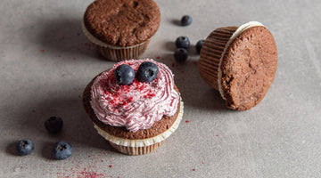 Low Carb Schokomuffins mit einer pinken Creme auf einem grauen Steinuntergrund.