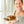 Laden Sie das Bild in den Galerie-Viewer, Matthias Steiner steht vor einer Fensterfront und trägt eine graue Schürze. In seiner Hand hält er einen weißen Teller mit einem STEINER´s Nusskuchen in Kastenform. Der Kuchen ist mit flüssiger Schokolade und gehackten Nüssen getoppt.