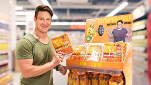 Matthias Steiner steht neben einem STEINER´s Produkt-Display in einem Lebensmittelmarkt. Er hält eine Packung STEINER´s Low Carb Brötchen in die Kamera.