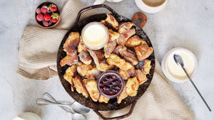 Zubereiteter Kaiserschmarren aus STEINER´s Low Carb Kaiserschmarrn Backmischung in einer gusseisener Pfanne.  Serviert mit Joghurt-Topping und einen Beerenkompott.