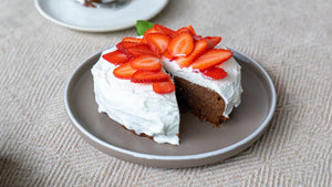 STEINER´s Schokokuchen, serviert auf einem grauen Teller. Der Schokokuchen ist getoppt mit Quark und frischen Erdbeerscheiben.