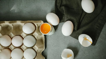 Eier als ganze Eier und 1 Ei geöffnet, Gelbei zu sehen
