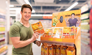 Matthias Steiner im Lebensmitteleinzelhandel vor einem Display mit STEINER´s Low Carb Produkten, er hält eine Packunge Brötchen in der Hand