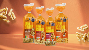 Unsere vier Sorten STEINER´s Pasta uf Haferfaser-Basis. Locken-Spätzle, Fusilli, Rigatoni und Tagliatelle. Die Verpackungen stehen vor einem Hintergrund in Orange.