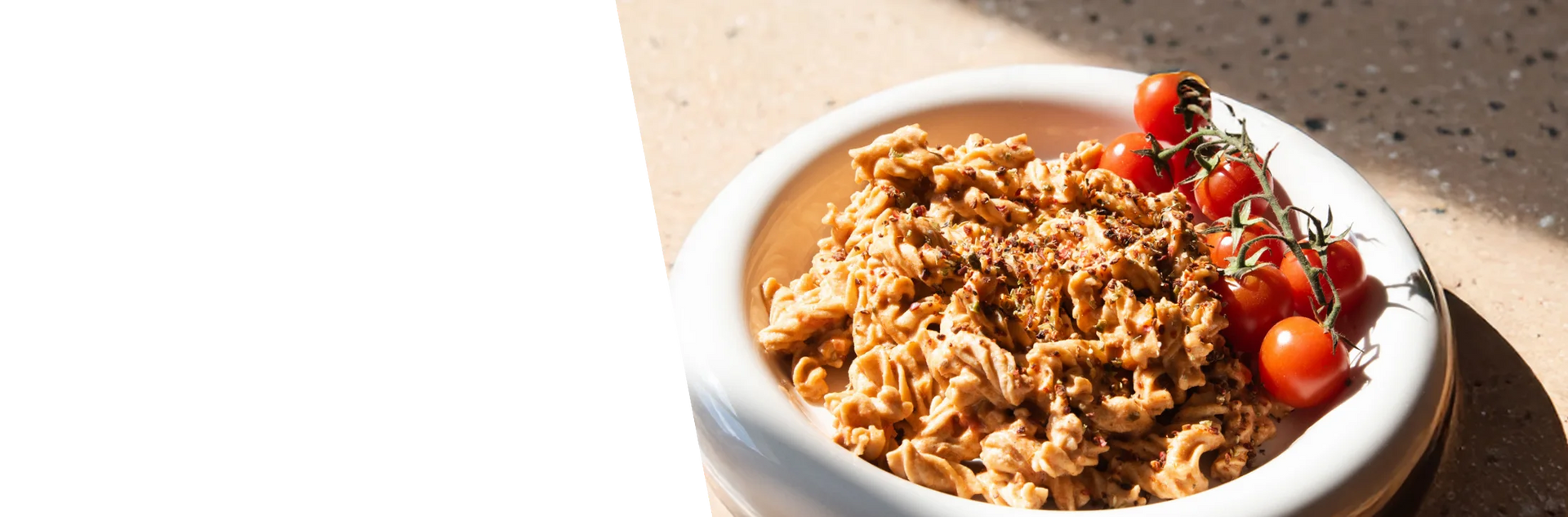Zubereitete STEINER´s Low Carb High Protein Fusilli mit einer Tomaten-Sahne-Soße auf einem runden Teller.