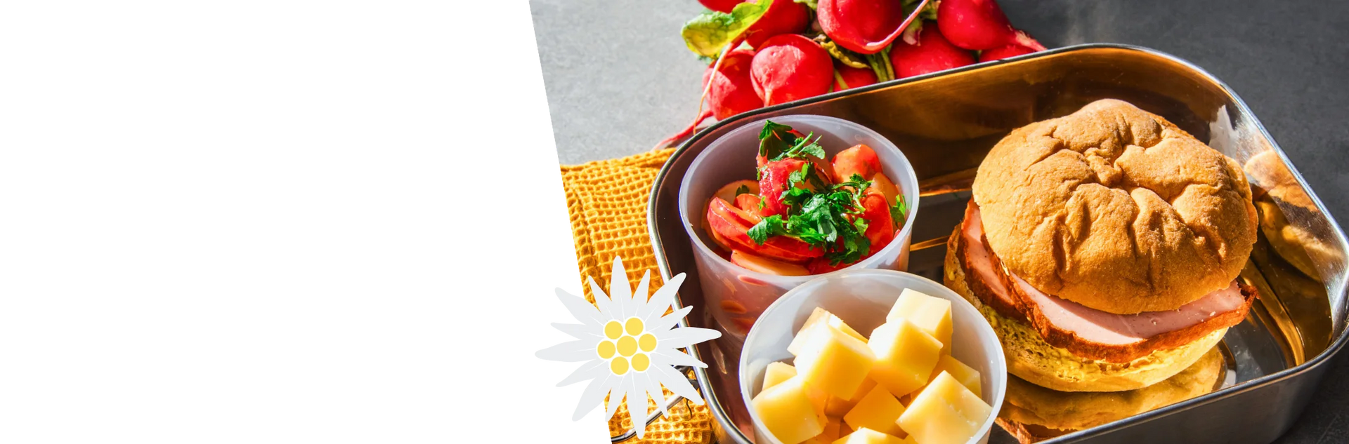 Oktoberfest-Brotzeit mit einer Leberkässemmel aus einem STEINER´s Low Carb High Protein Bun. Dazu Käsewürfel und Tomaten-Radieschen-Salat in einer ToGo-Box.
