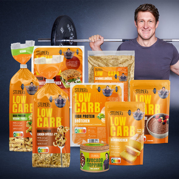 STEINER´s Kennenlern Deal Box mit Low Carb Produkten wie Nudeln, Brötchen und Gewürz. Matthias Steiner ist mit Hantelstange ist im Hintergrund.