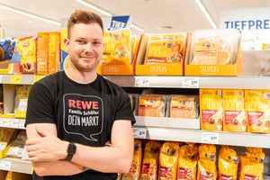 Rewe Marktleiter vor einem STEINER´s Regal.