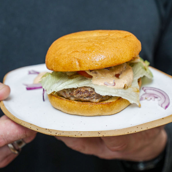 STEINER´s Low Carb High Protein Burger Buns begelgt mit einem Burgerpatty aus Rindfleisch, Salat und einer Low Carb Burgersoße.