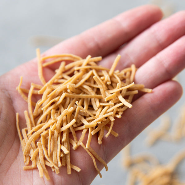 In einer Hand befindet sich eine handvoll ungekochteSTEINER´s Low Carb High Protein Suppeneinlage.