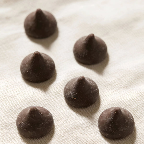 Sechs STEINER´s Zartbitter Schokodrops auf einem weißen Leinentuch.